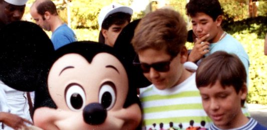 a group of people posing for a picture with a person in a mouse garment