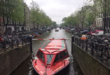 Cracks Already Showing In Capital One’s Purchase Of Discover For Travelers a red boat in a canal with bicycles and buildings