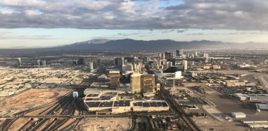 a cityscape with a golf course and a mountain in the background