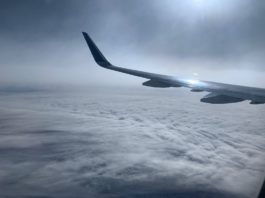 Image of a plane wing above the clouds, as seen from an airplane window