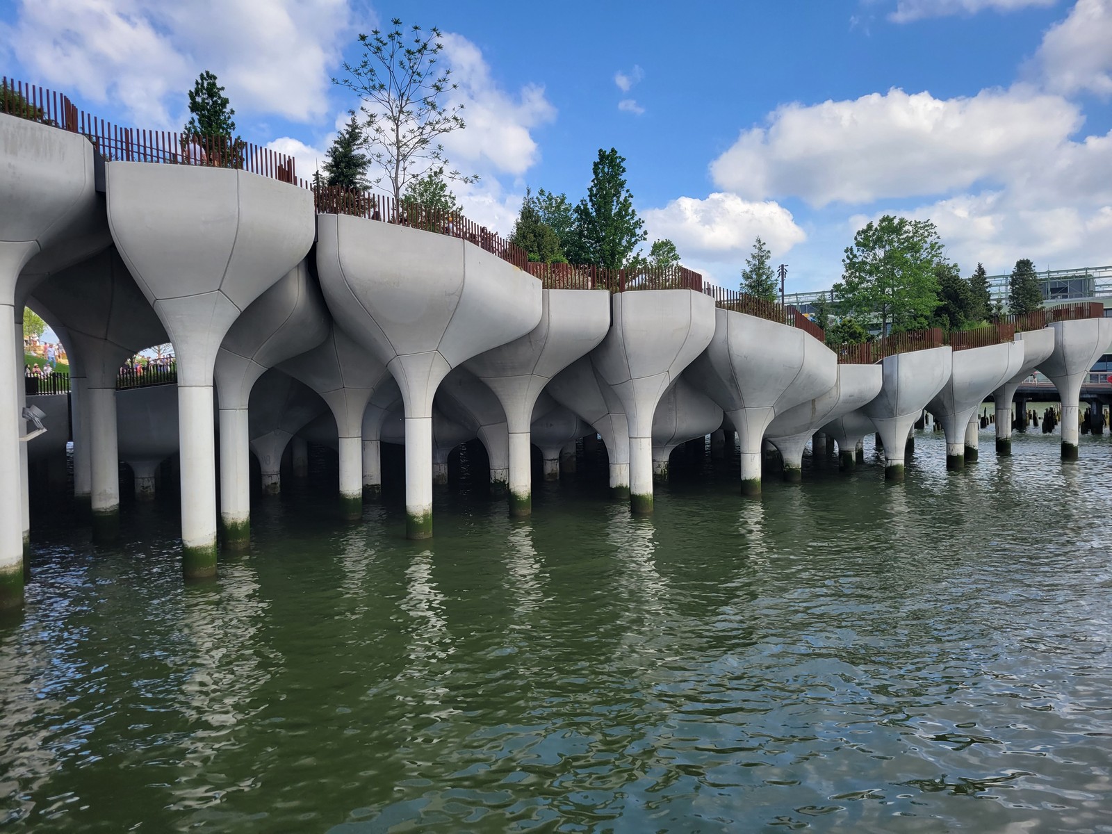 a bridge over water with trees and a blue sky