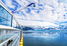 Hot Demand, Royal Caribbean Needs to Hire Thousands of Employees a cruise ship on a body of water with mountains in the background