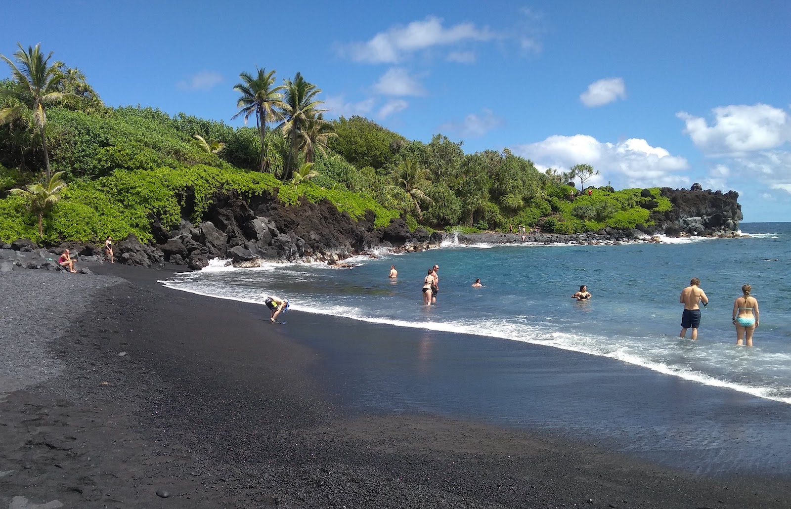 A view of people on the black sand beach at Wai’anapanapa State Park in Maui