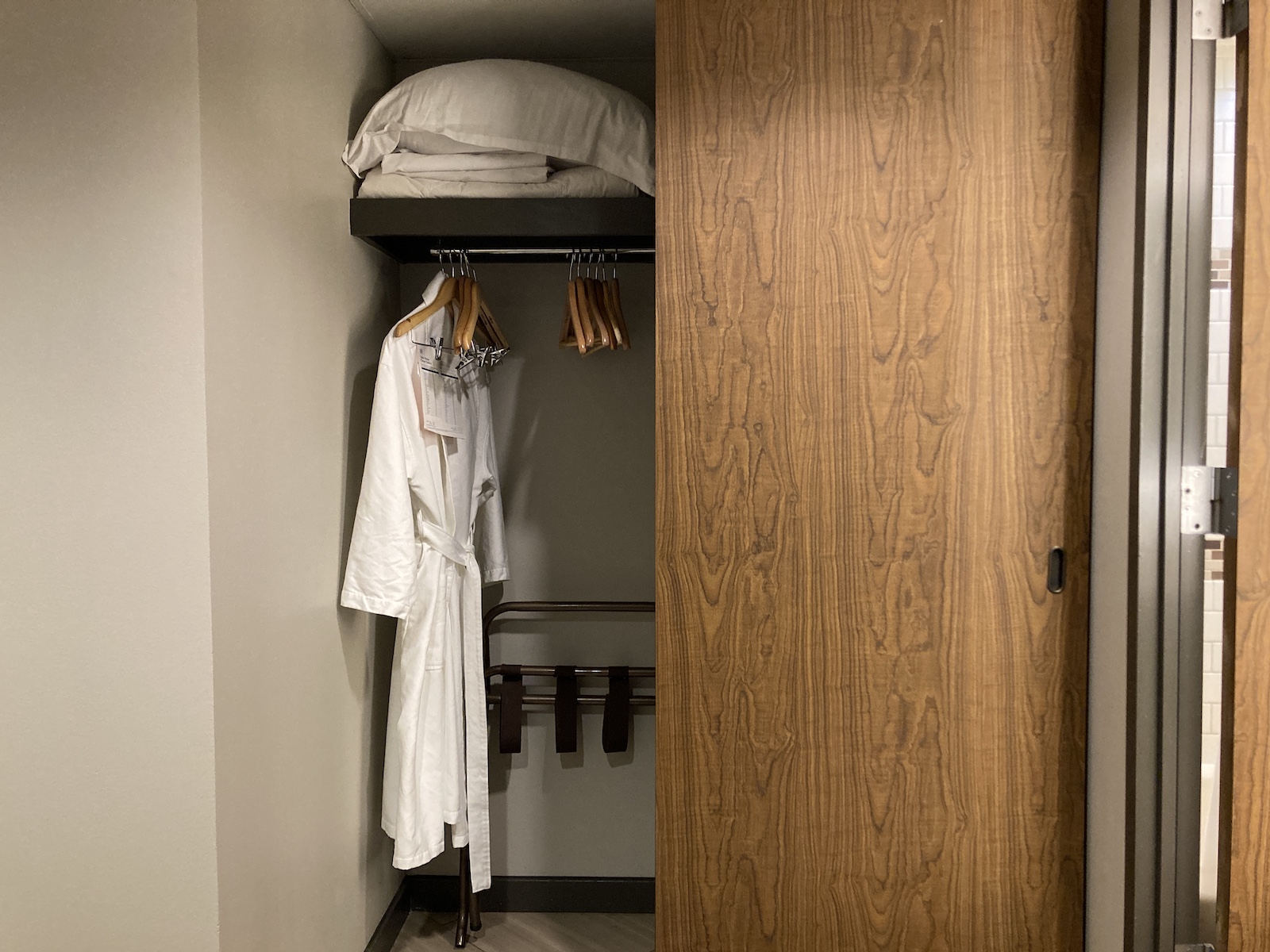 Photo of half-open closet showing robes and bedding supplies