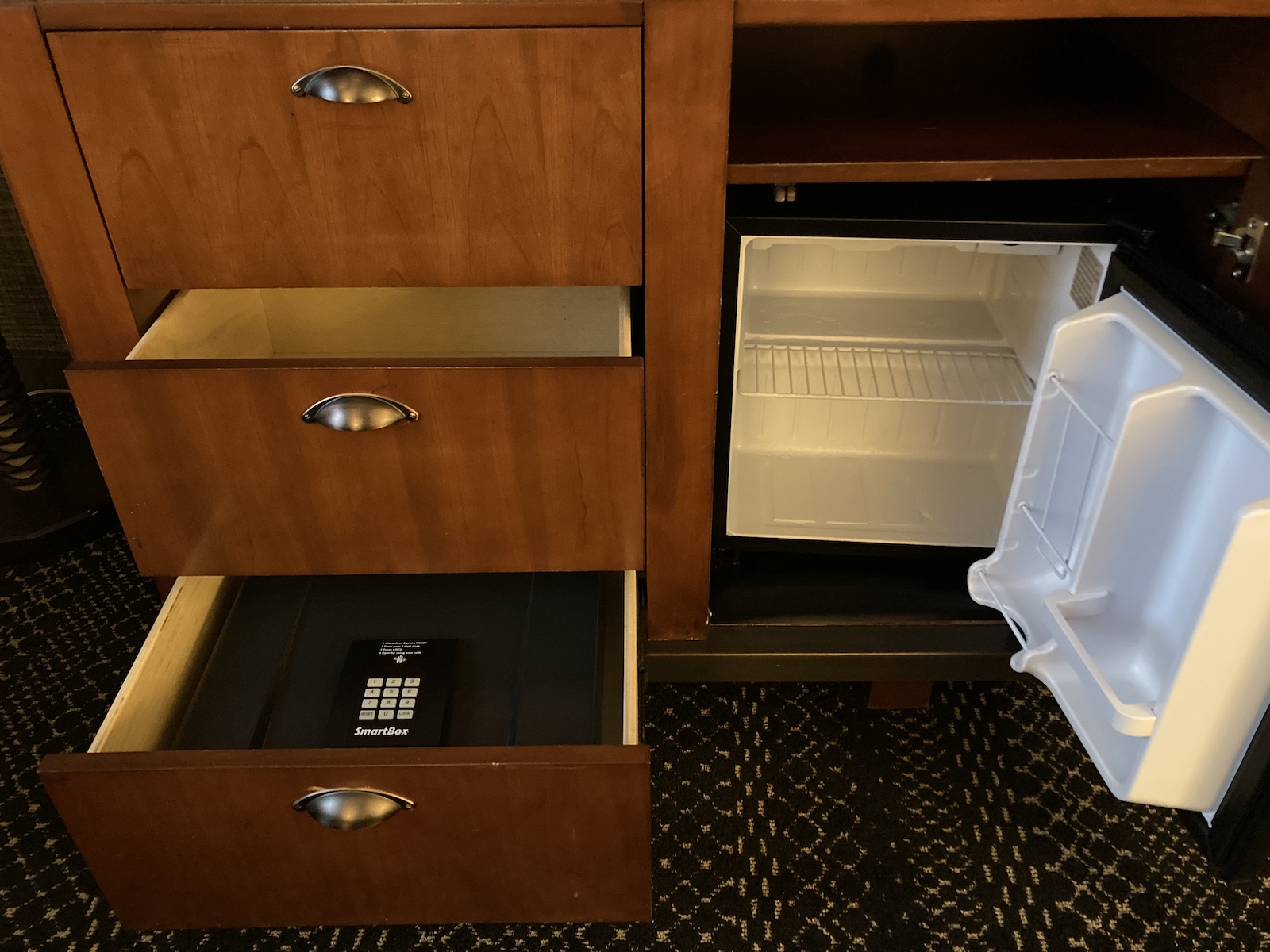 Photo shows drawers, safe, and mini fridge inside the dresser