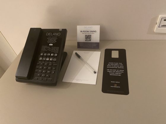 Phone, notepad and guest information on the desk in the hotel room