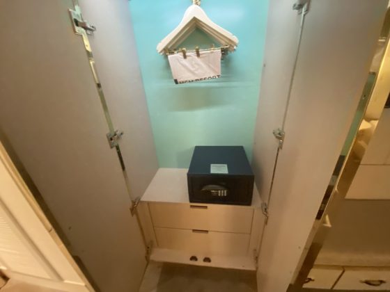Image of opened closet with iron and ironing board, plus a safe and some drawers