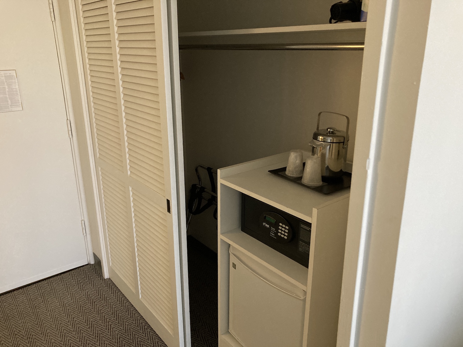 Image of closet with 1 door open, showing a safe and ironing board inside