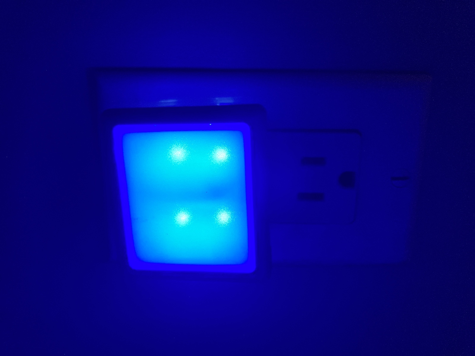 A blue nightlight is lit up in a wall socket