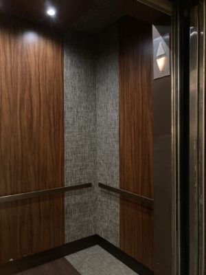 Photo of wood paneling inside softly-lit elevator