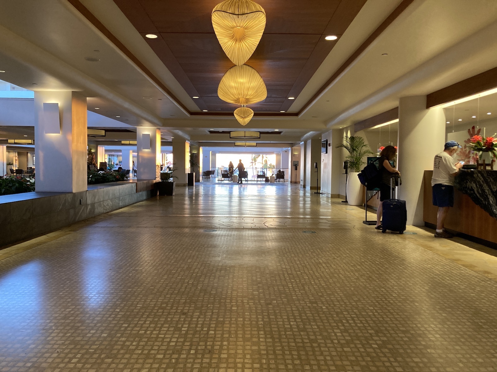 Photo of open lobby with a few people waiting in line at the reception desk at Waikoloa Beach Marriott Resort Spa