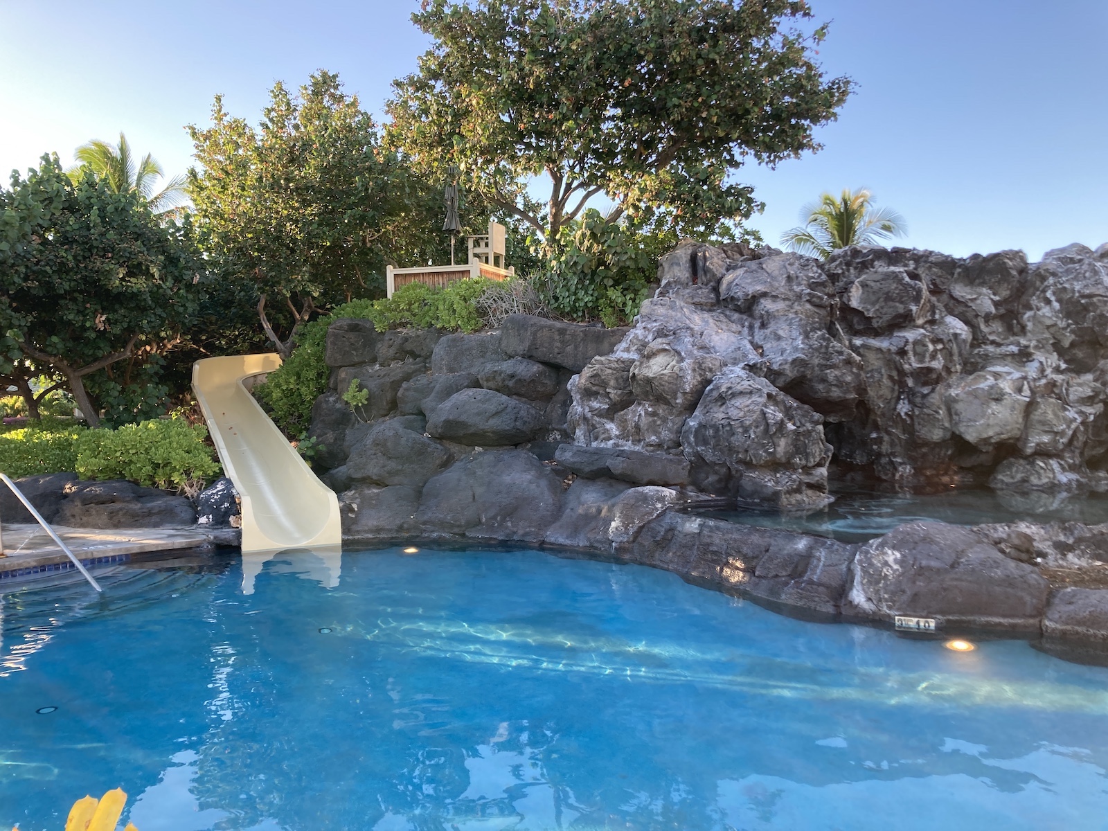Photo of a water slide coming down from some rocks into a pool below