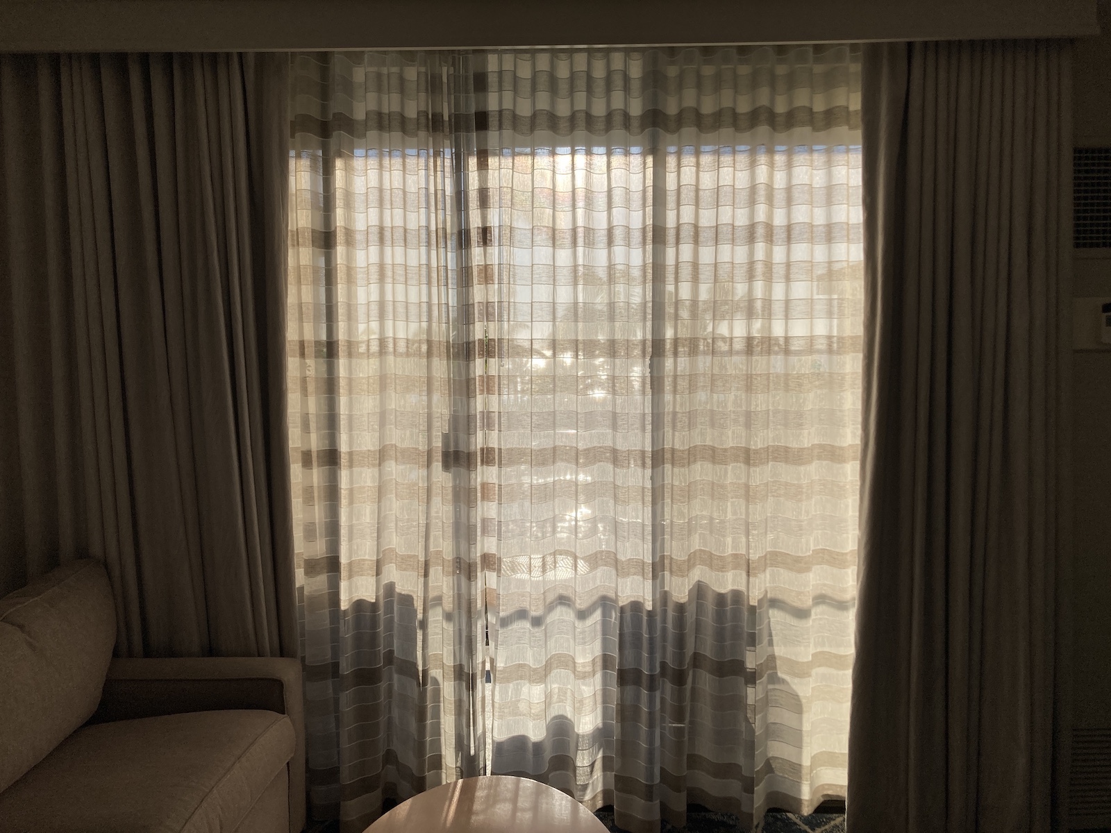 Image shows curtains closed over glass doors with sunshine beyond