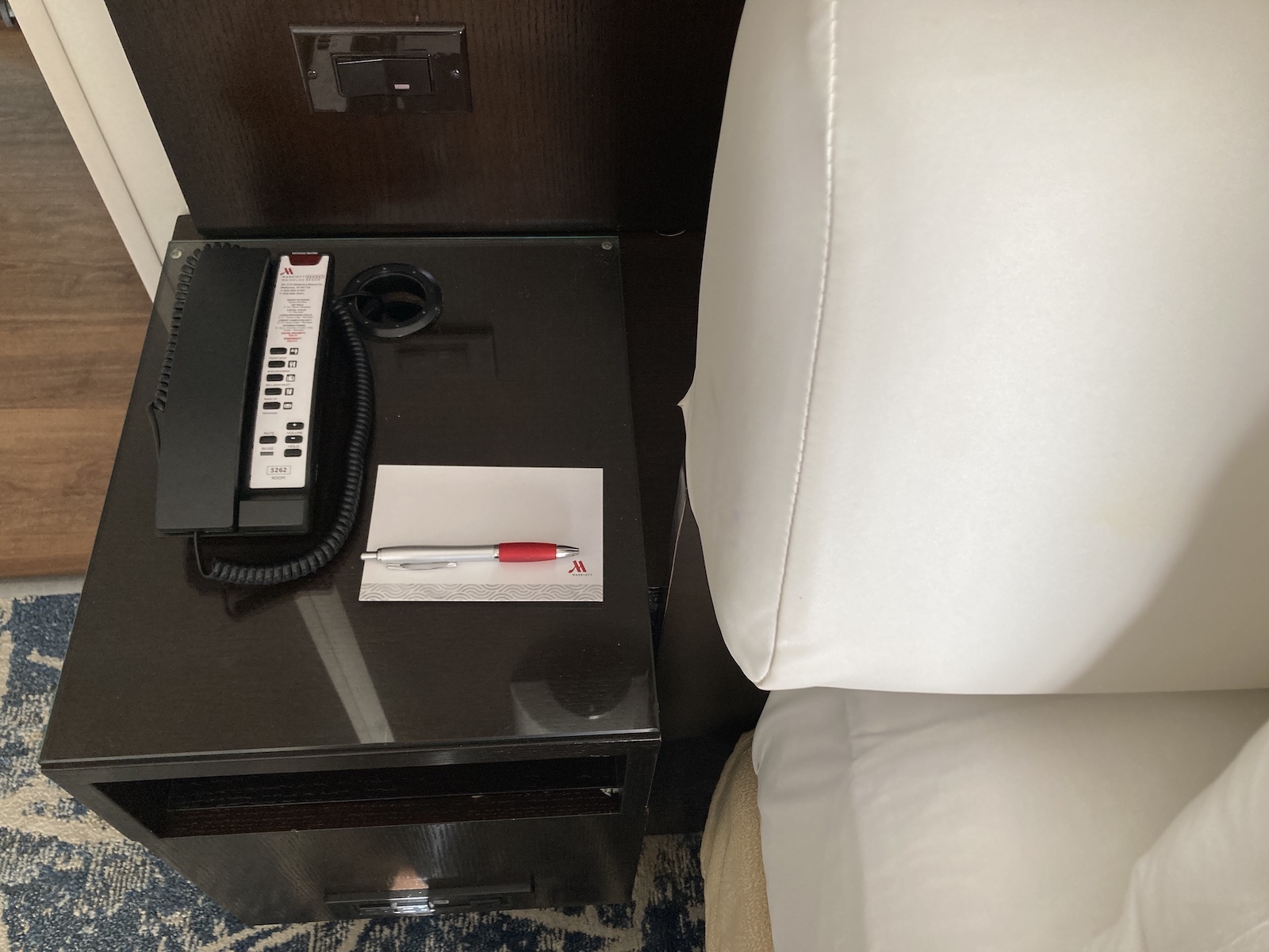 Photo of a nightstand with notepad and phone on it