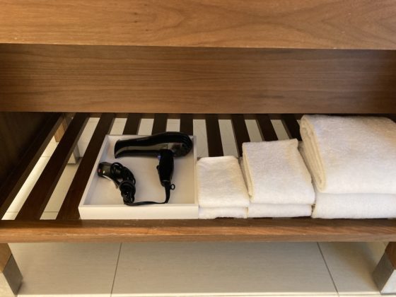 Photo of shelving under sink holding towels and hairdryer