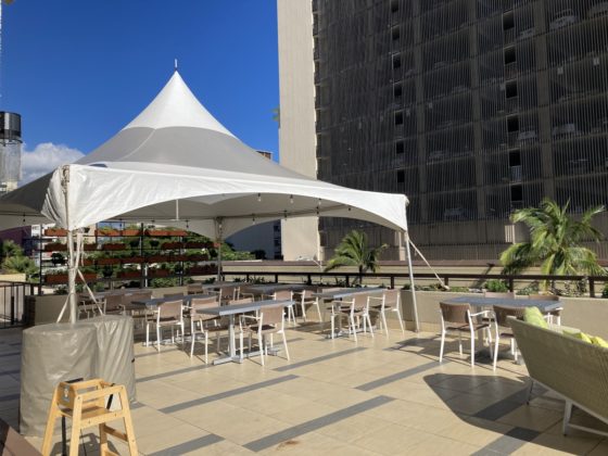 Photo of empty tables covered by an awning on the outdoor patio of the Regency Club