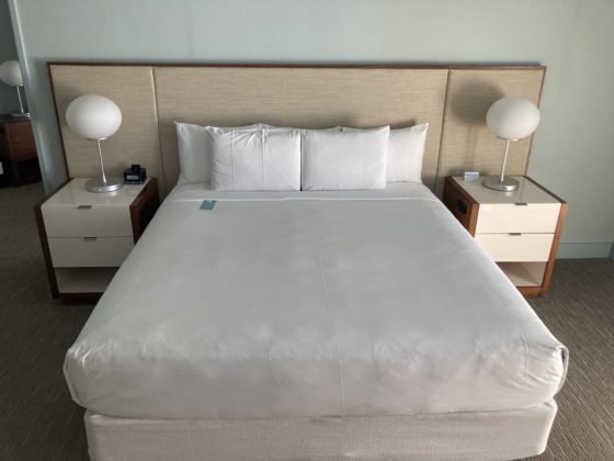 Photo of king size bed with white covers and pillows, flanked by 2 night stands