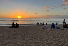 Marriott Adds More Flexibility to Free Night Awards a group of people sitting on a beach at sunset