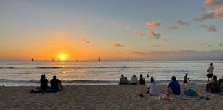 Marriott Bonvoy Boundless Card Offering 5 Free Nights and $100 Airline Credit a group of people sitting on a beach at sunset