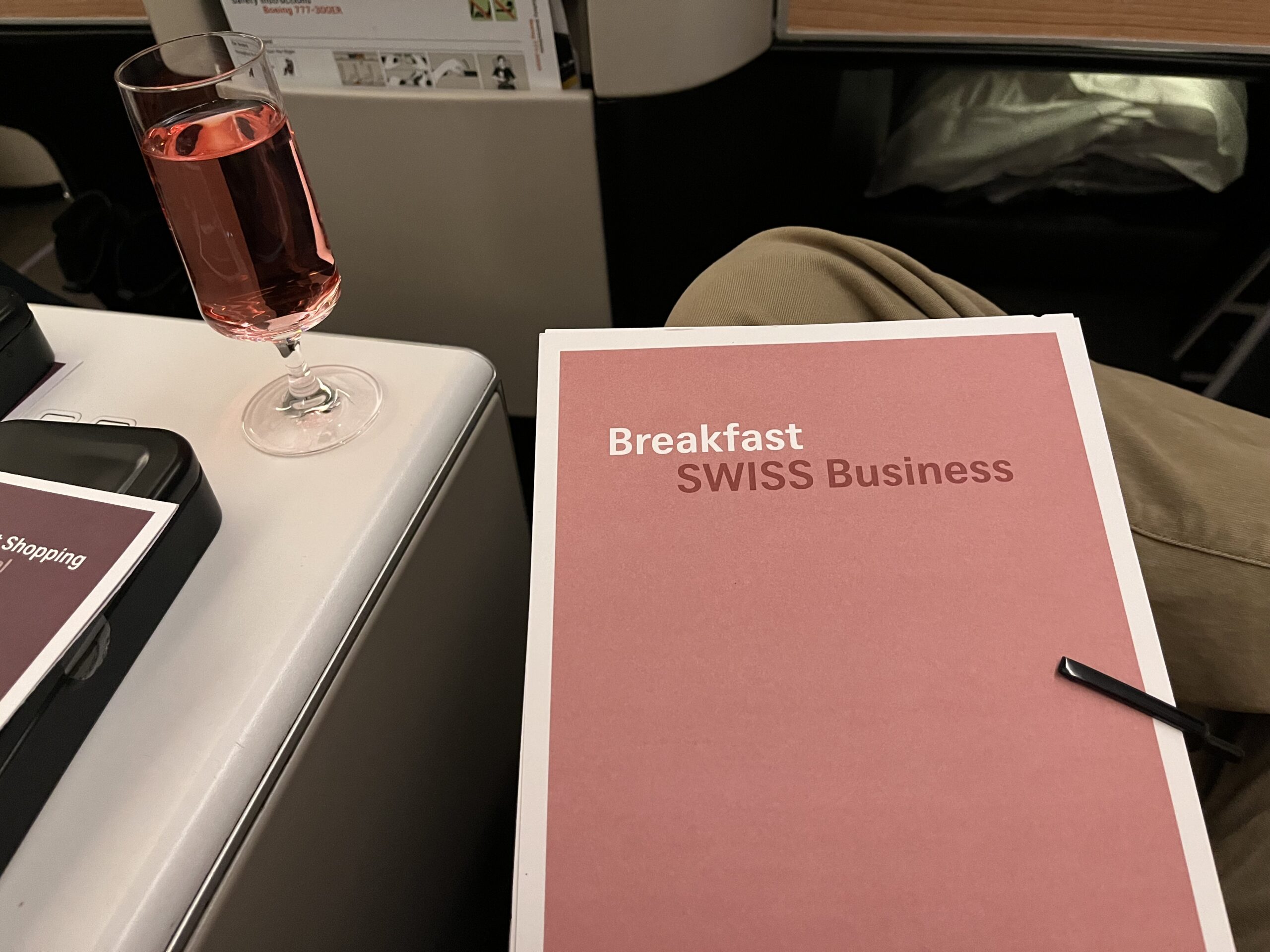 a pink folder with a pen and a glass of liquid on a table