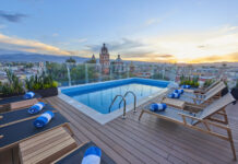 Marriott Bonvoy Bold Card Refresh with Best Ever Bonus and New Benefits a pool with chairs and a deck with a view of a city