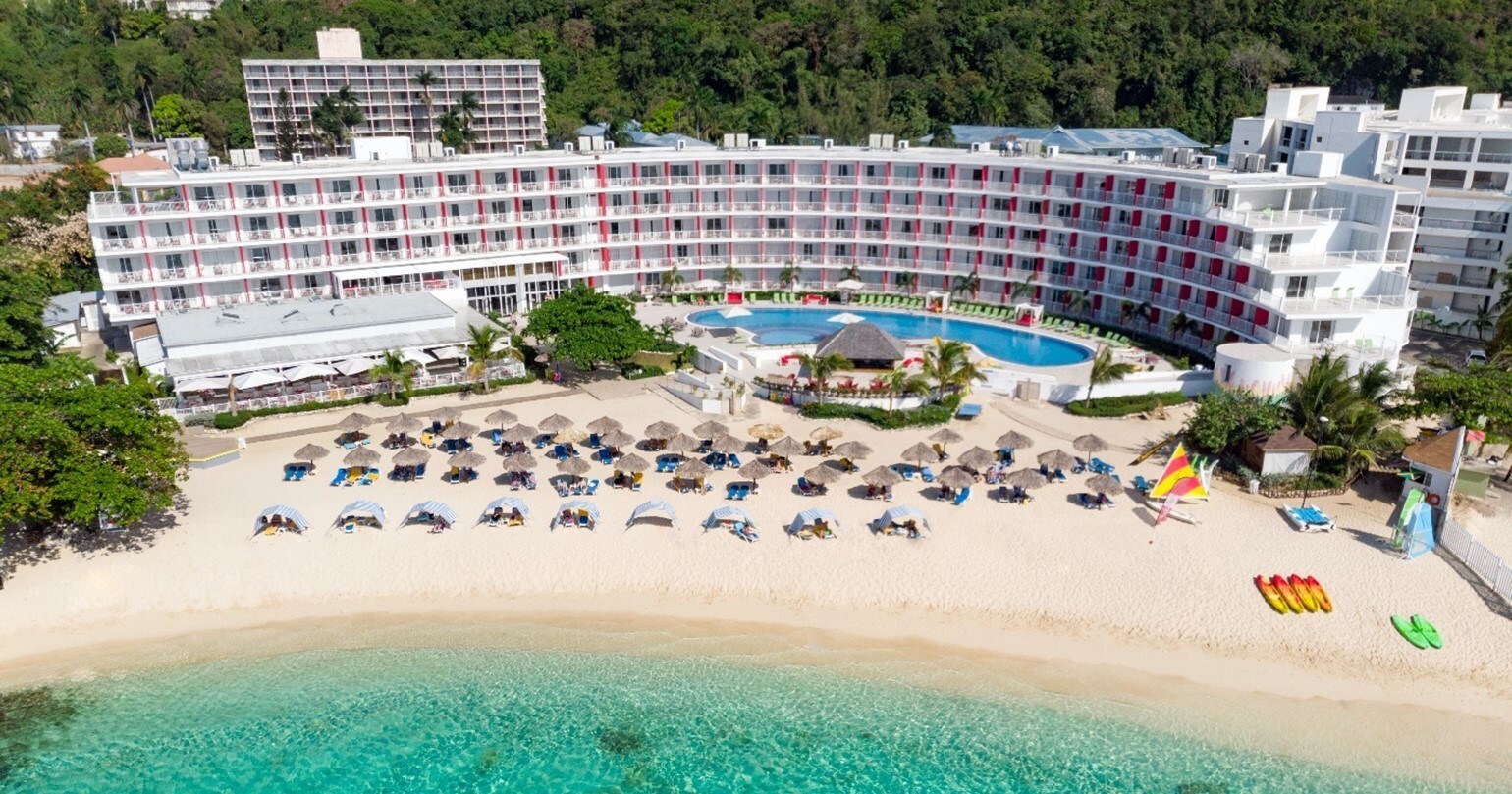 a hotel with a pool and umbrellas on a beach