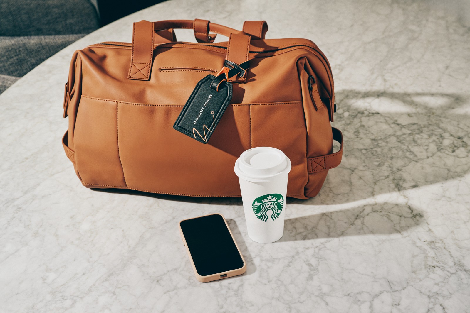 a brown bag with a coffee cup and a phone on a marble surface