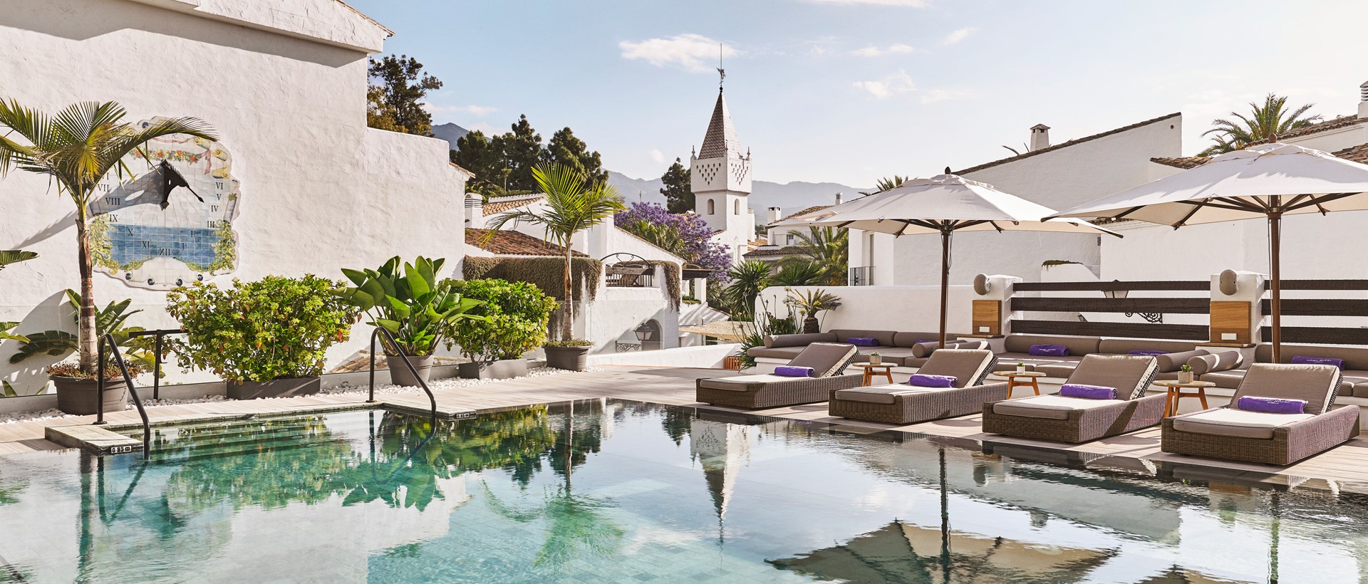 a pool with lounge chairs and umbrellas in front of a building