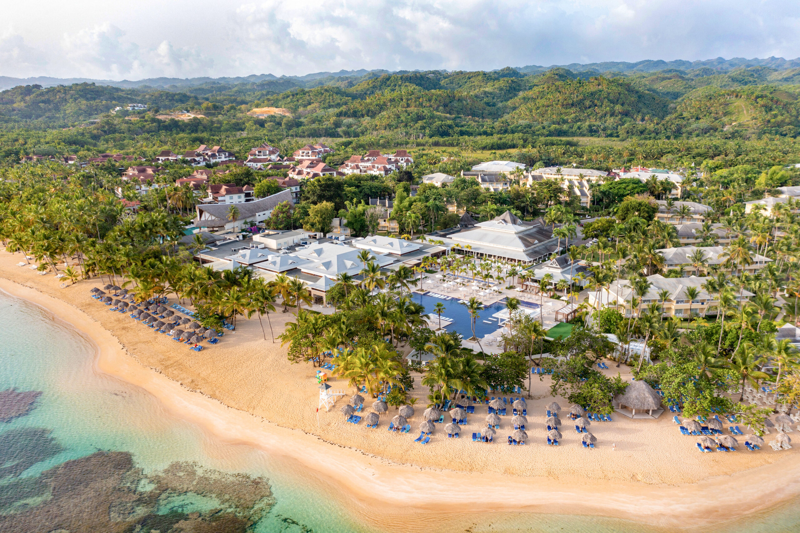 a beach with a group of buildings and trees