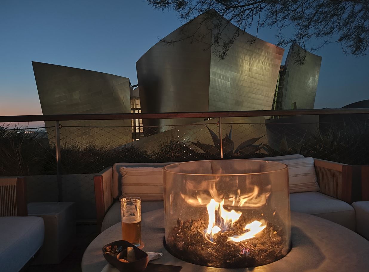 a fire pit on a table with a glass bowl and a beer on it