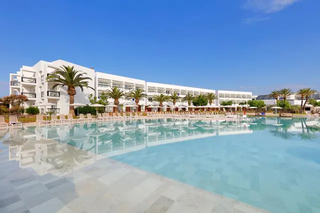 a pool with chairs and a building in the background