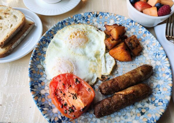 a plate of food with eggs sausage and tomatoes